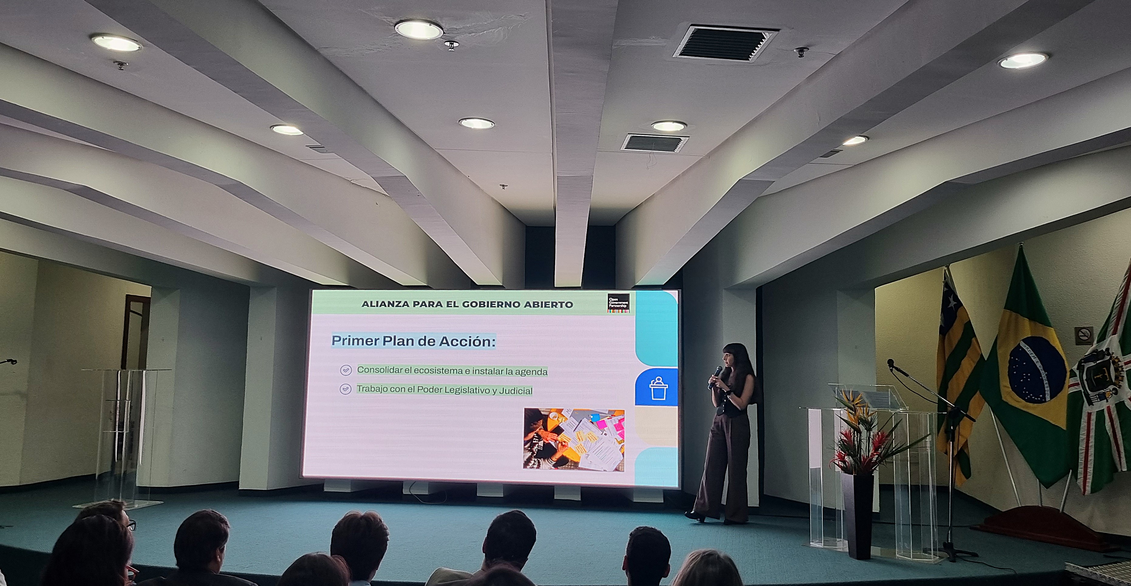Personas reunidas en una sala viendo una presentación en pantalla grande