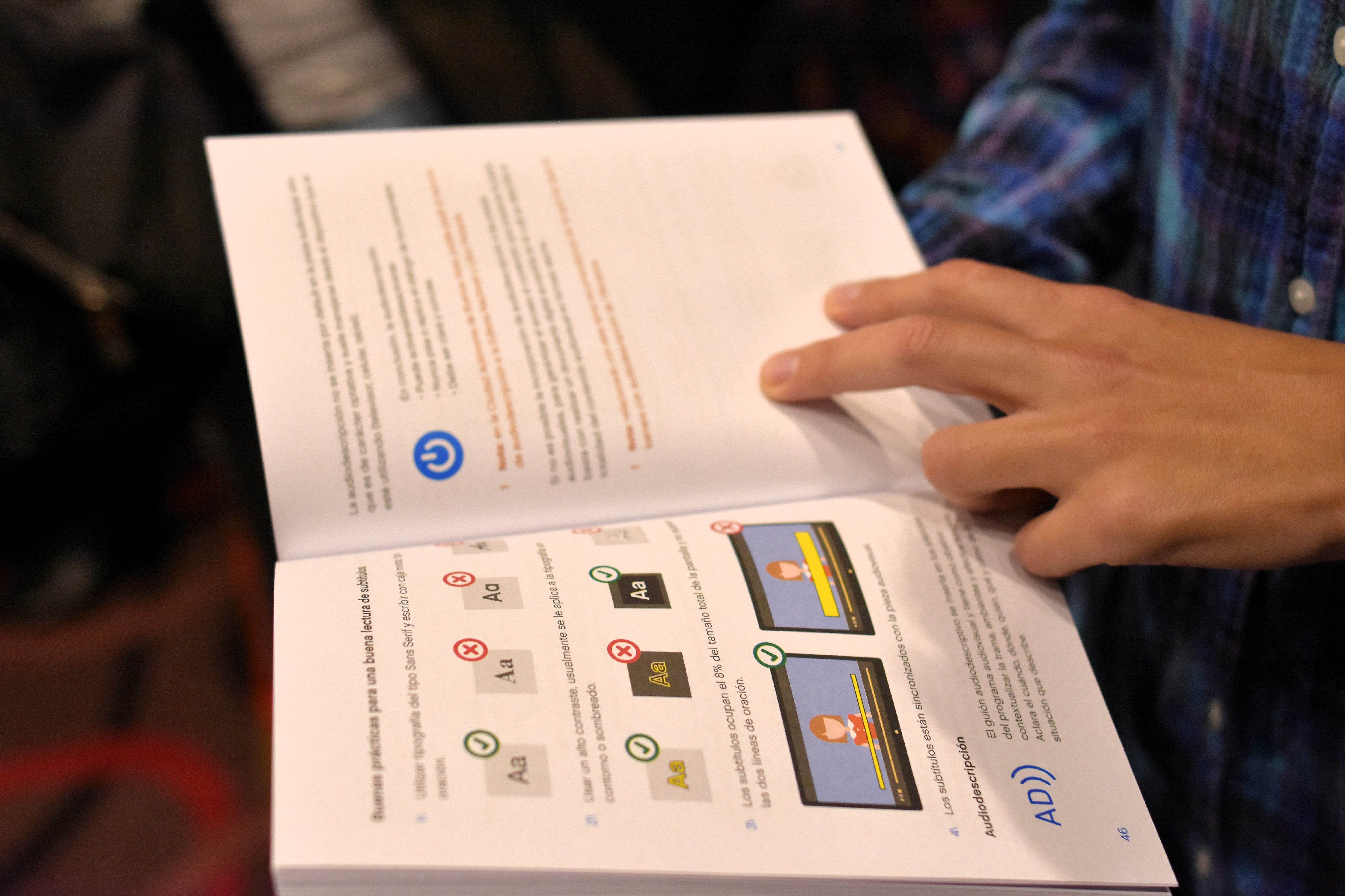 Fotografia de una persona sosteniendo el manual en postura de lectura. De la persona solo se observa parte del torso y la mano izquierda