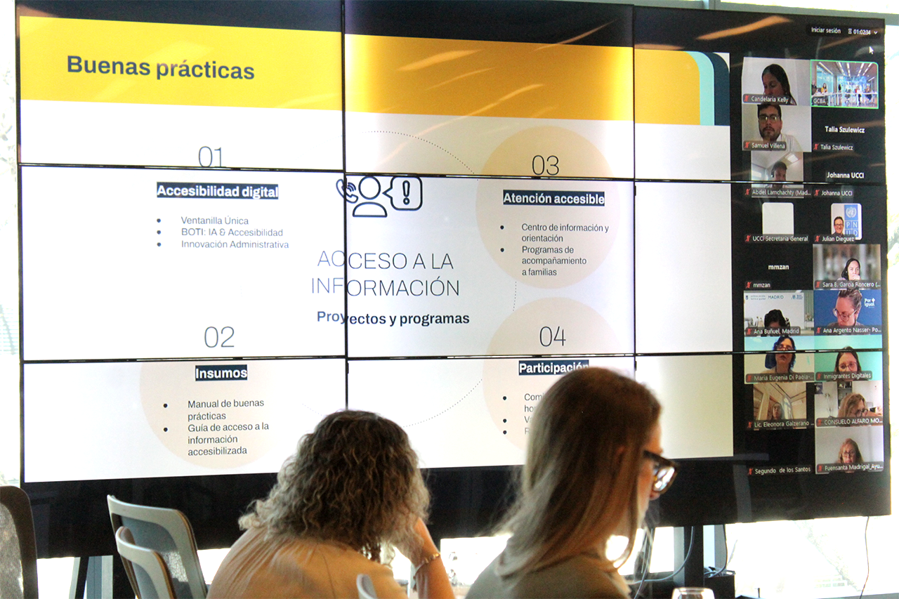 Personas participando en un seminario híbrido sobre accesibilidad digital, con pantalla que muestra la presentación de buenas prácticas y oradores conectados de manera virtual.