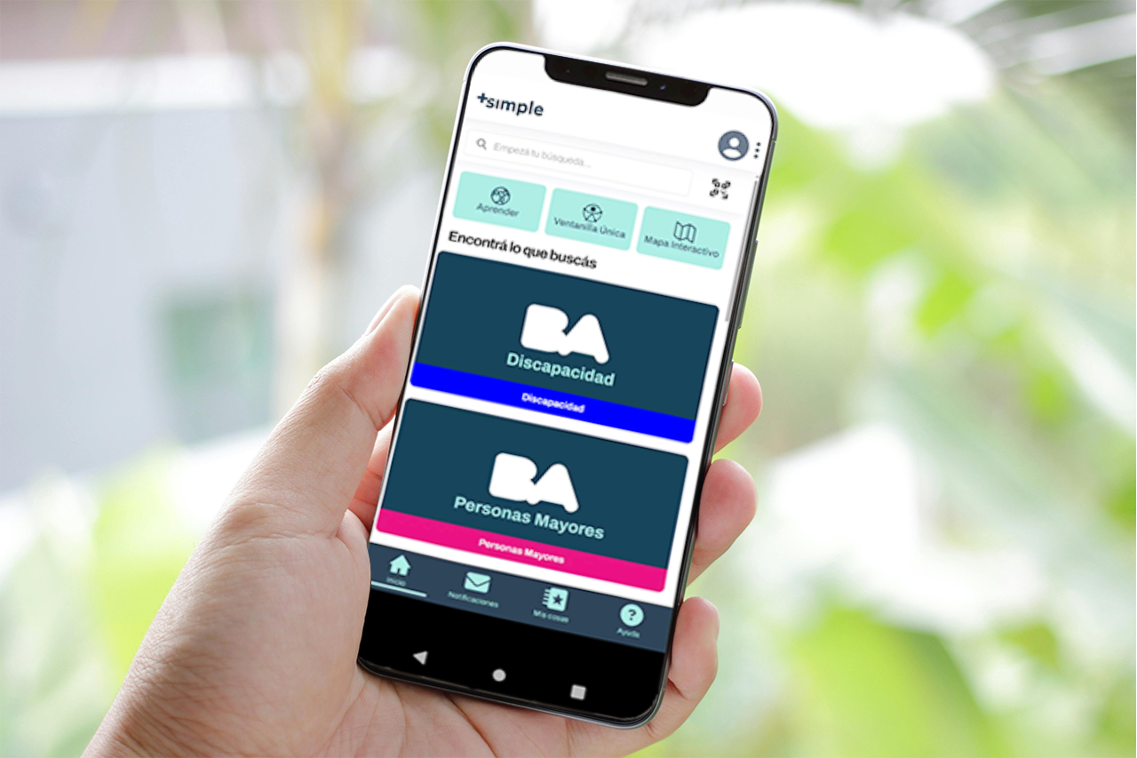 Persona sosteniendo un celular con la app Club+Simple abierta en la sección de Discapacidad y Personas Mayores