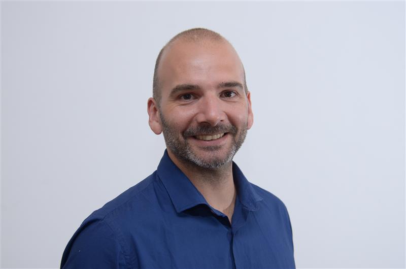 Perfil frontal de Franco Maffoni, con camisa azul, en un retrato con fondo neutro.