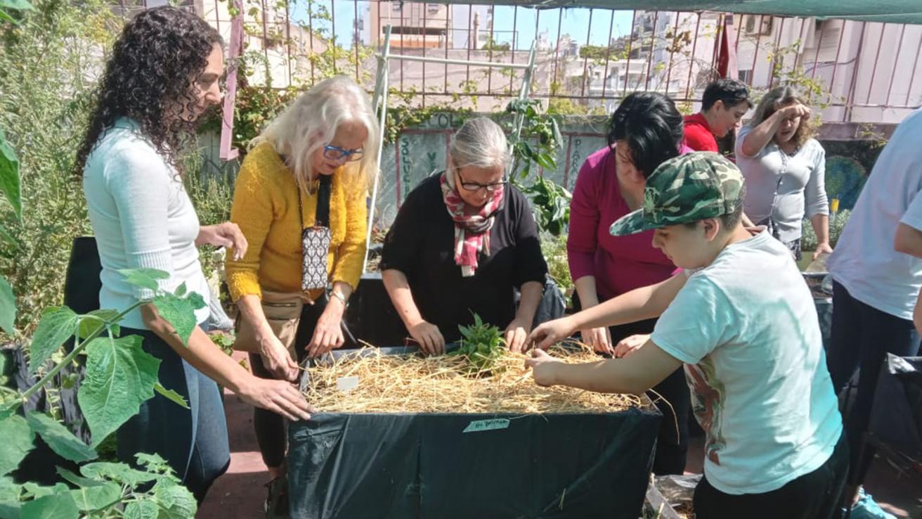 Mujeres y niños siembran almacigos en una terraza
