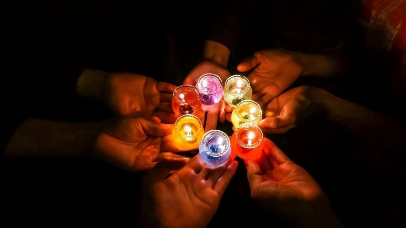 manos acercandose con una velita de color