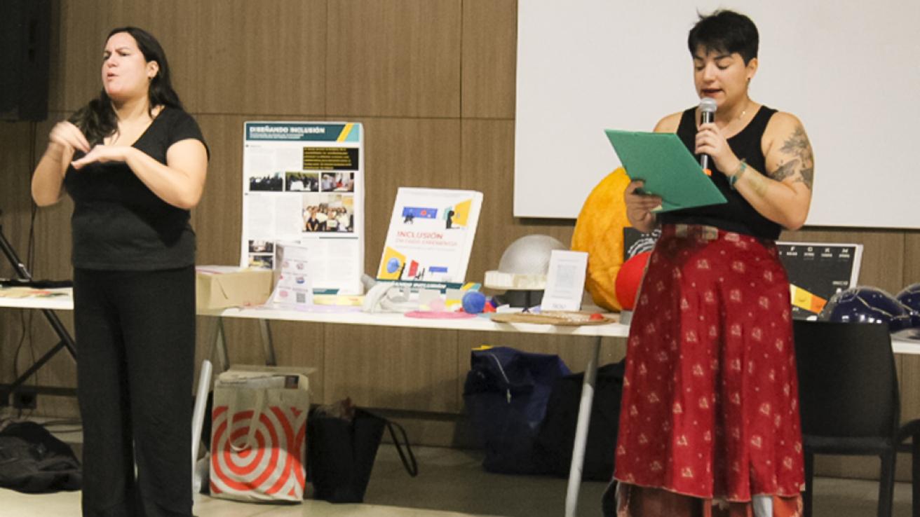 Una mujer intérprete de Lengua de Señas Argentina interpreta el documento que lee otra persona con micrófono en mano durante una actividad de capacitación.