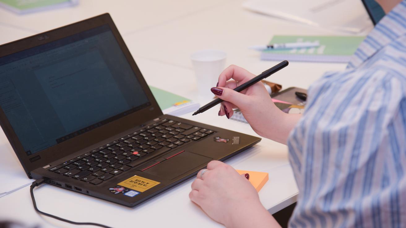 Persona escribiendo con una notebook en el escritorio