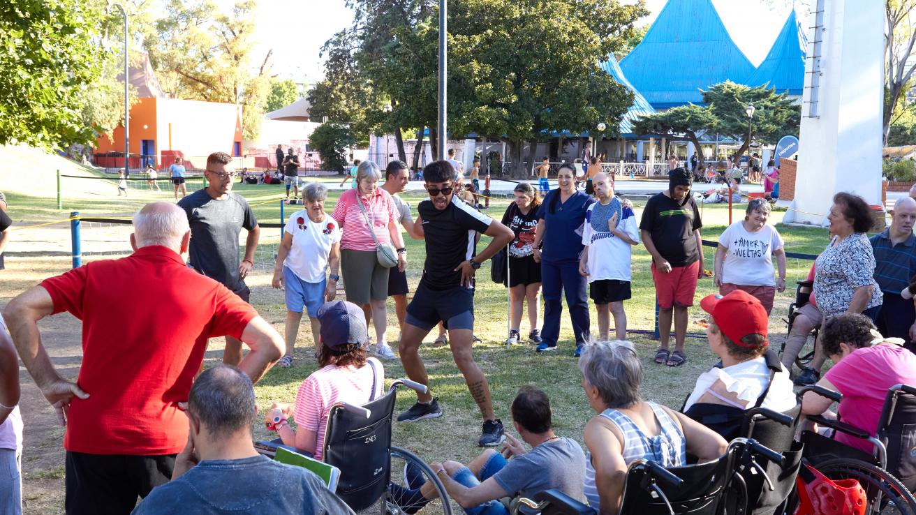 Personas adultas con discapacidad participan de una actividad recreativa accesible en el Parque de la Ciudad, acompañadas por un profesor, en un entorno comunitario.
