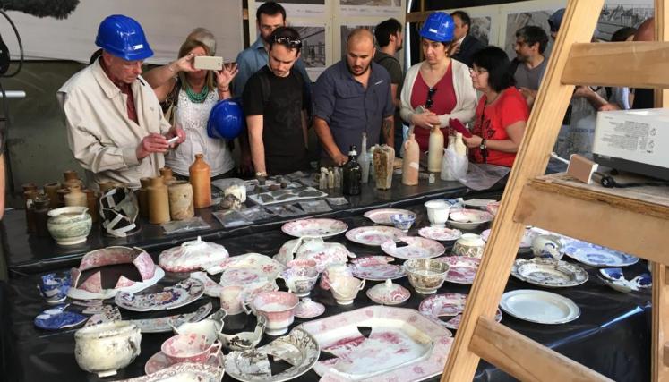 Muchas personas mirando una mesa con piezas arqueologicas