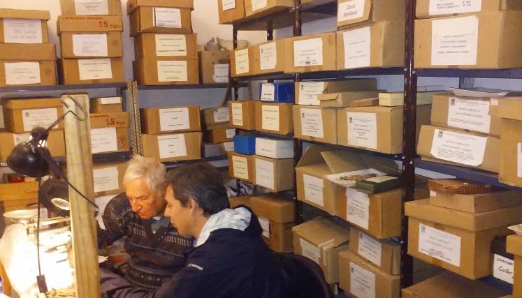 Estanterias con muchas cajas y dos personas sentadas 