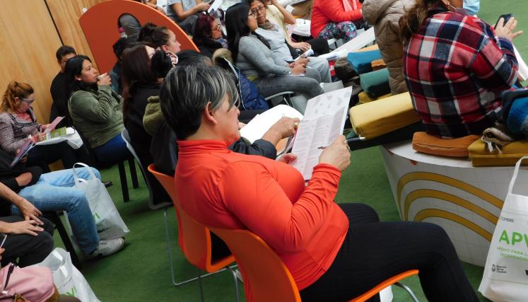 Fotografía tomada en lateral derecho del grupo de APVIS en formación. En ella se encuentran todos sentados y cada uno con acciones distintas donde destaca una mujer que lee el material entregado. 