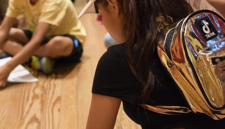 Nena con mochila dibujando en el piso