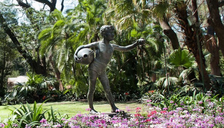 Estatua de bronce rodeada de flores