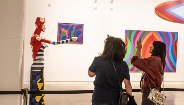 Dos personas viendo una exposición artística y sacando fotos