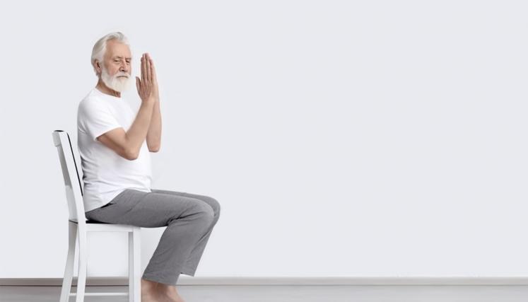 Hombre sentado en una silla con las manos juntas