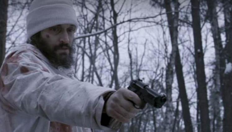 Hombre apuntando un arma en un bosque