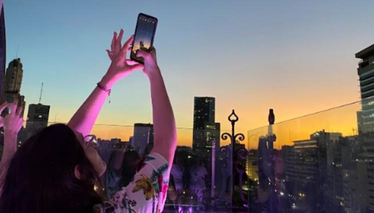 Persona sacando foto de la ciudad en altura con el atardecer