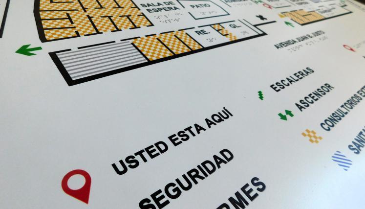Plano táctil accesible con información en braille, íconos y señalización del edificio indicando sectores como guardia, sala de espera, escaleras y ascensor.
