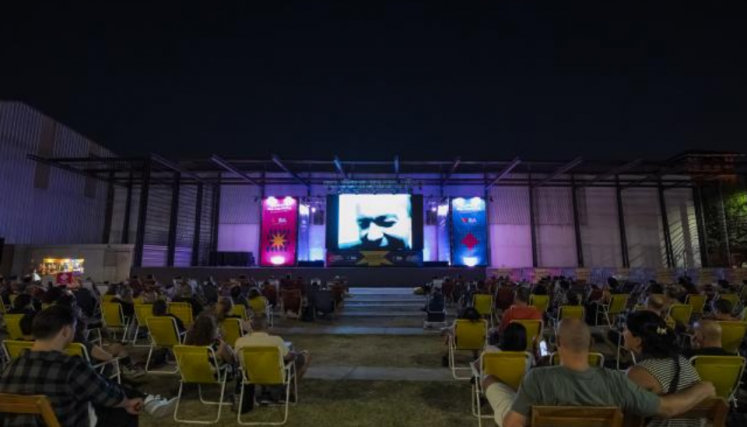 Personas sentadas en sillas mirando una película proyectada